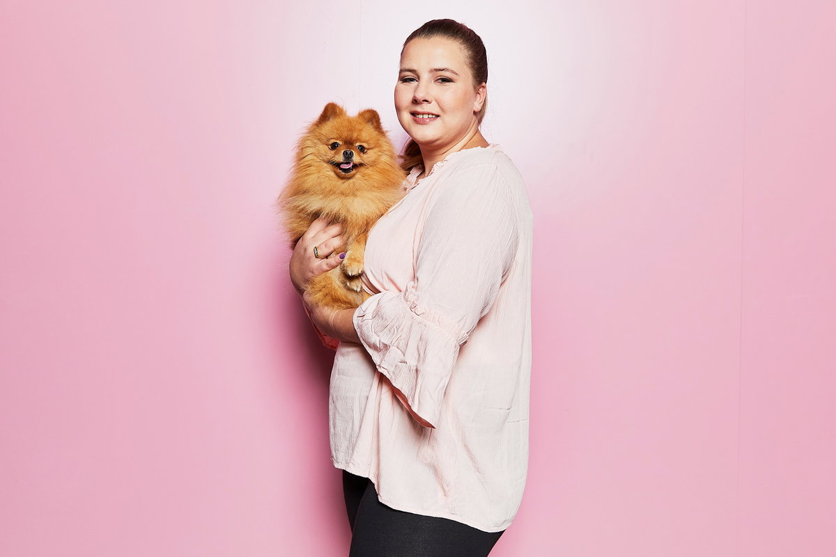 Sarafina Wollny mit Hund Feivel auf dem Arm vor einer pinken Wand