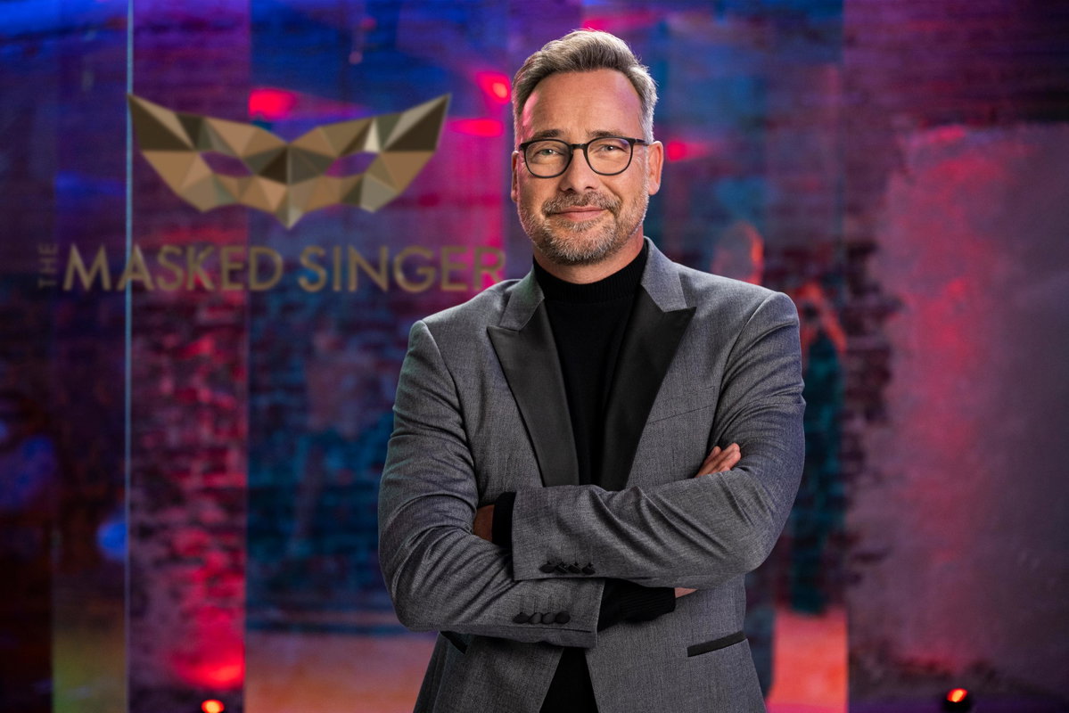 Matthias Opdenhövel vor dem "The Masked Singer"-Logo