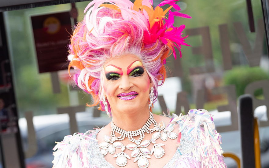 Olivia Jones stark geschminkt mit Federn im pinken Haar