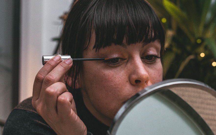 Frau zieht Eyeliner vor Spiegel