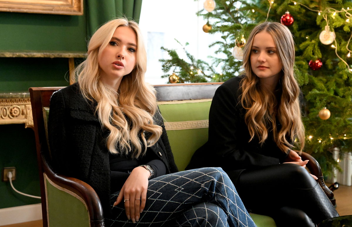 Davina und Shania Geiss sitzen auf einer Bank vor einem Weihnachtsbaum und gucken ernst