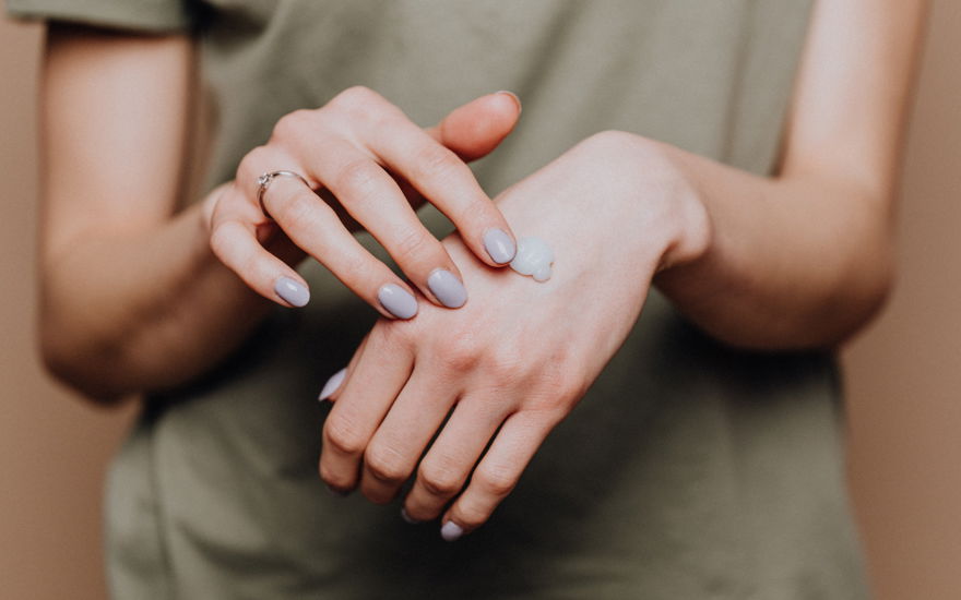 Frau cremt Hand ein