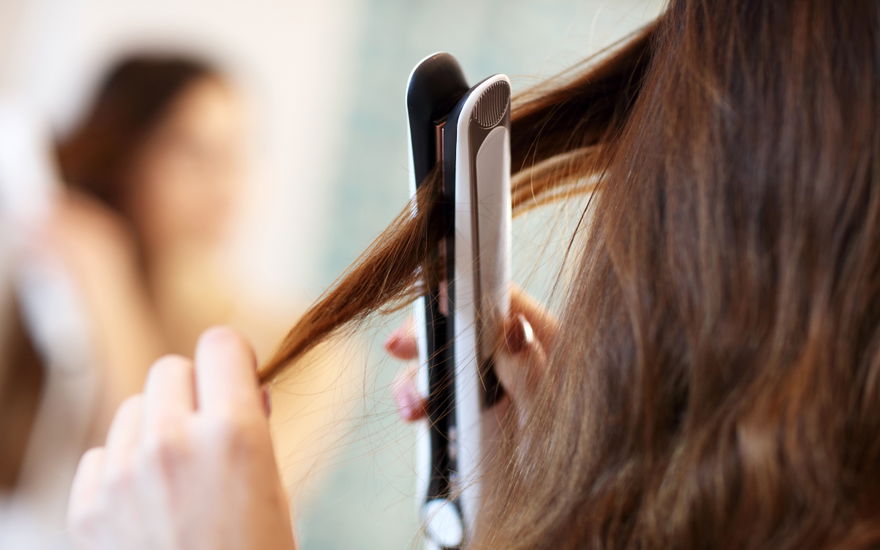 Frau glättet sich Haare