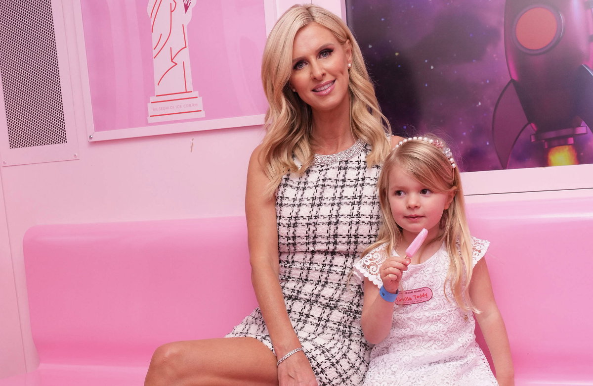 Nicky Hilton sitzt mit Tochter Teddy auf einer rosa Bank und isst Eis.