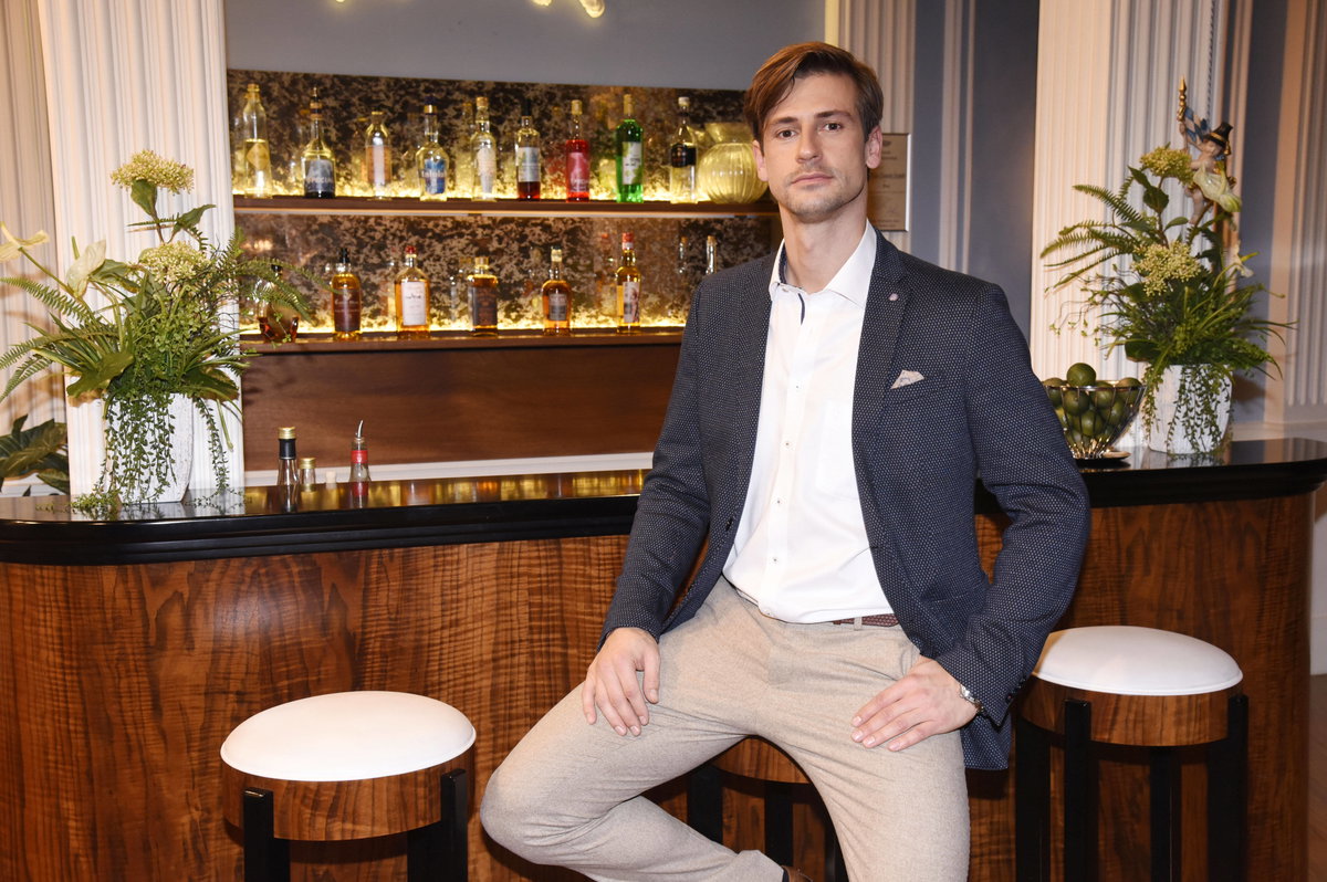 Sandro Kirtzel sitzt auf einem Hocker an einer Bar und guckt ernst