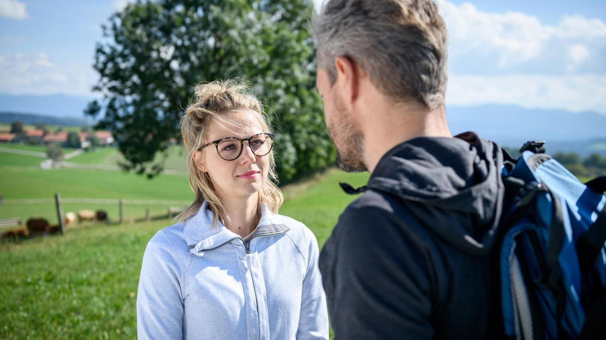 Sturm der Liebe Josie lächelt leicht und schaut Erik an, der mit dem Rücken zur Kamera steht