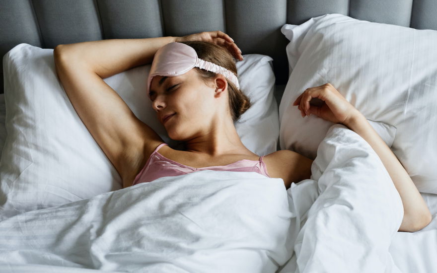 Frau liegt mit Schlafmaske im Bett