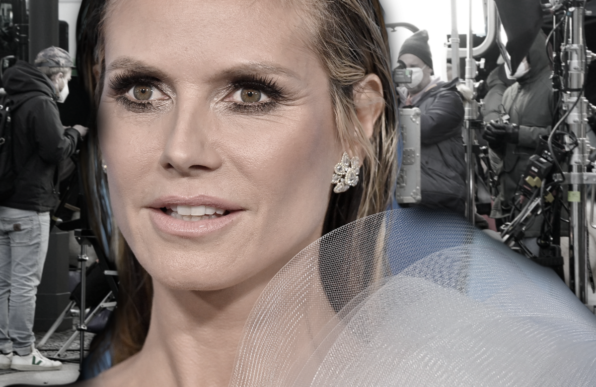 Heidi Klum guckt ernst, im Hintergrund das GNTM-Set