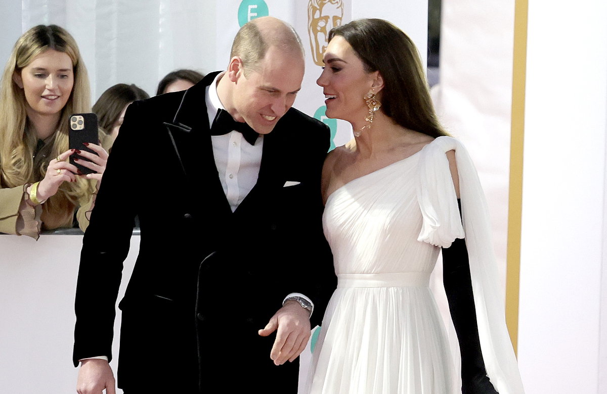 Prinzessin Kate flüstert Prinz William auf dem Roten-Teppich etwas zu.