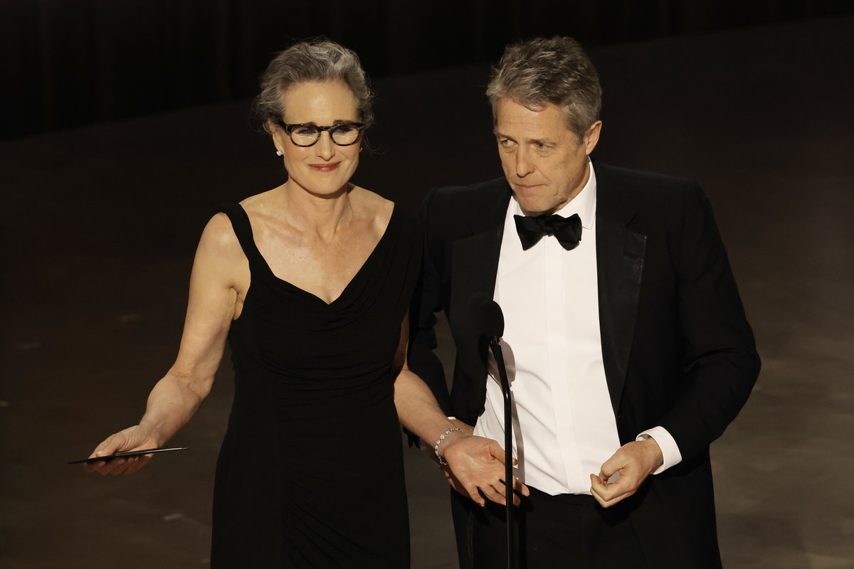 Andie MacDowell und Hugh Grant stehen vor einem Mikro auf der Bühne bei den Oscars 2023