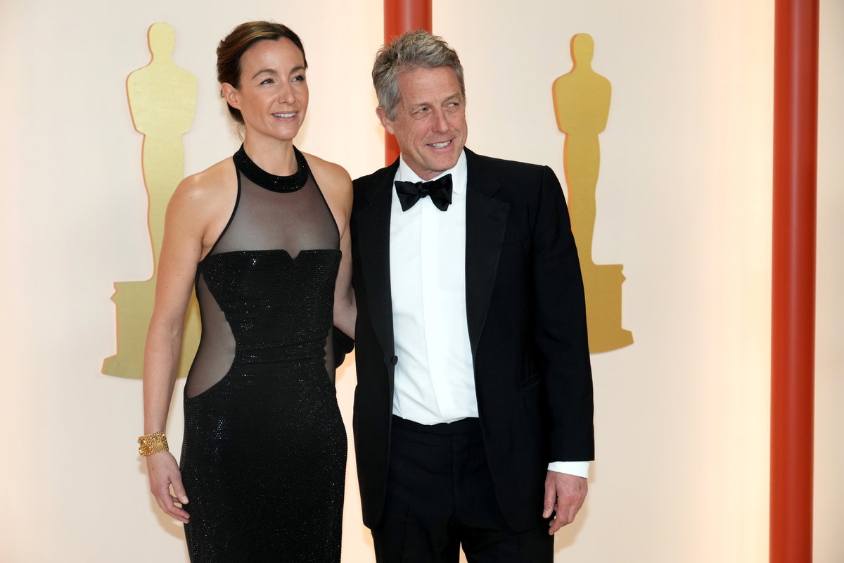 Anna Eberstein und Hugh Grant stehen Arm in arm auf dem Teppich bei den Oscars 2023