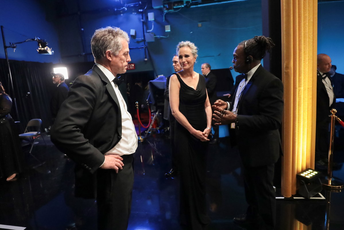 Hugh Grant steht bei den Oscars 2023 Backstage mit den Händen in die Hüfte gestemmt