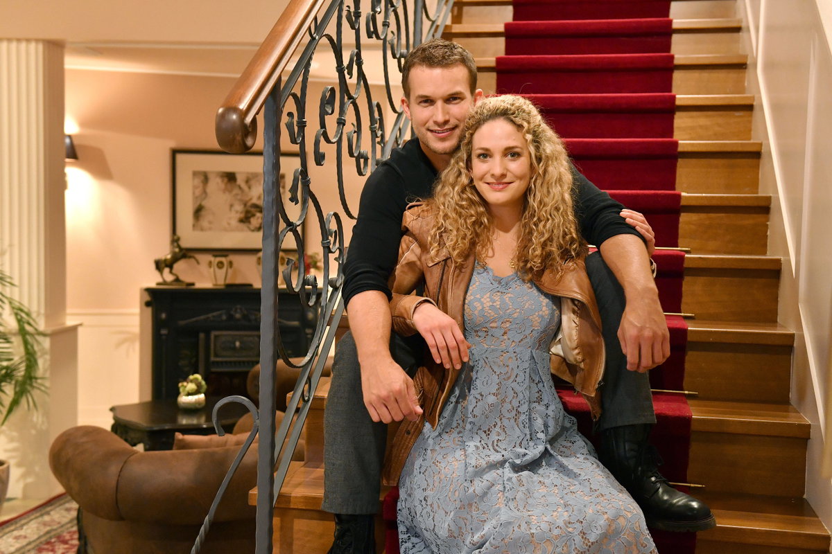 Lea Wegmann und Florian Frowein sitzen auf einer Treppe, sie sitzt zwischen seinen Beinen
