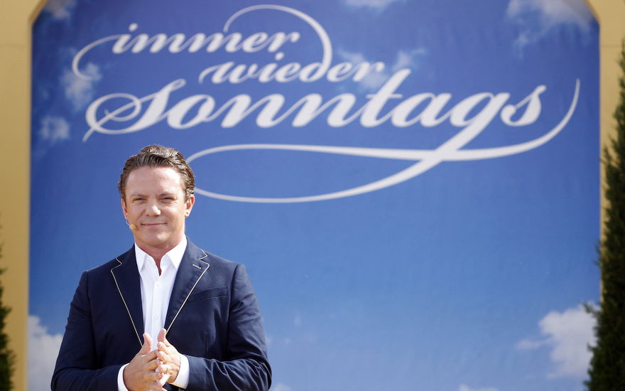 Stefan Mross mit Immer wieder sonntags Logo im Hintergrund