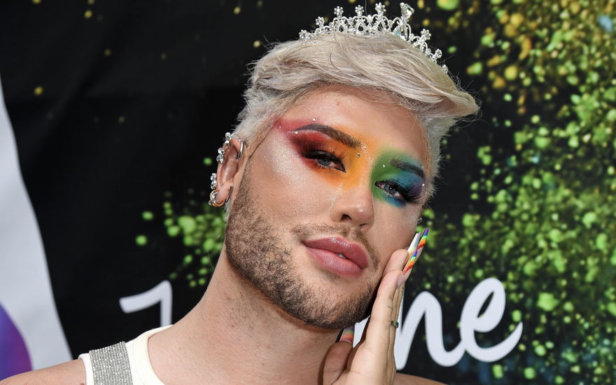 David Lovric mit Regenbogen Make-up und hand an der Wange.