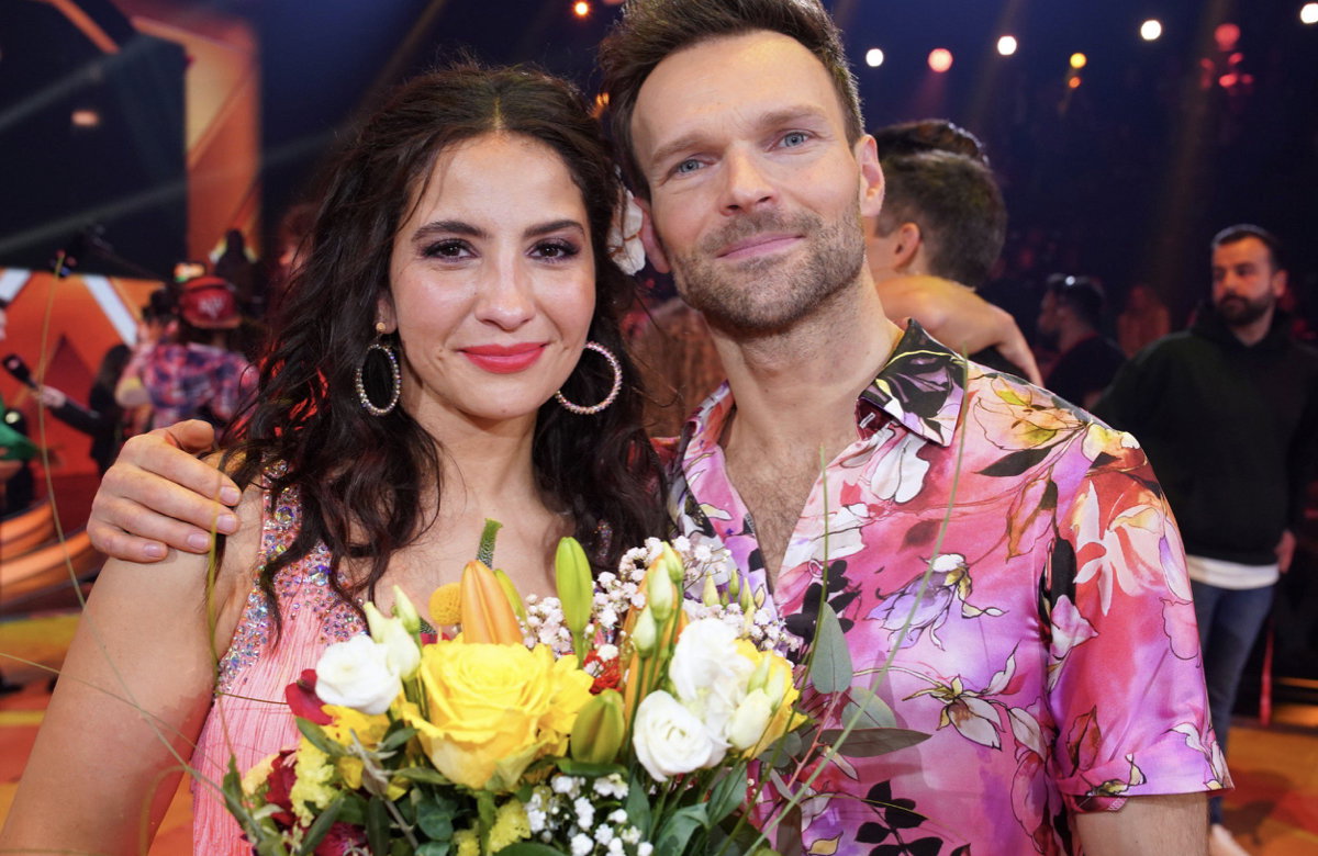 Chryssanthi Kavazi hält einen Blumenstrauß in der Hand und Vadim Garbuzov umarmt sie