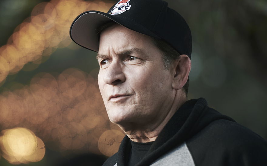 Charlie Sheen trägt eine Cap und einen Hoodie, sieht betroffen zur Seite
