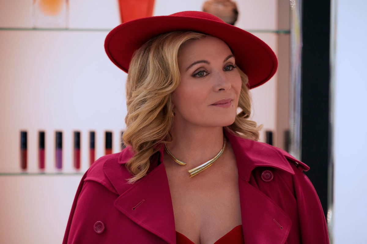 Kim Cattrall trägt in "Glamorous" einen pinken Trenchcoat mit passendem Hut