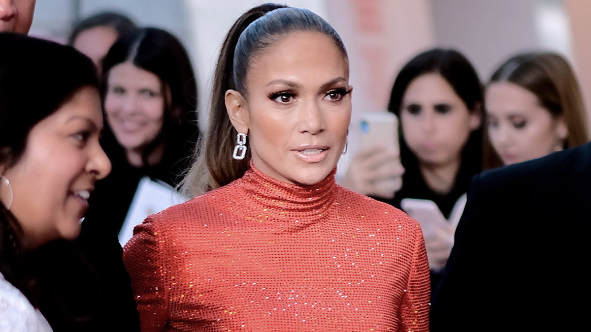 Jennifer Lopez geht in einem roten Glitzerkleid durch eine Menschenmenge