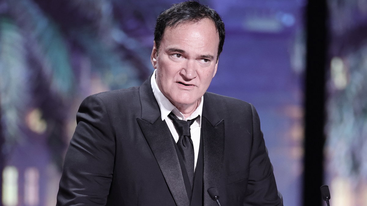 Quentin Tarantino steht mit ernstem Gesichtsausdruck am Mikrofon