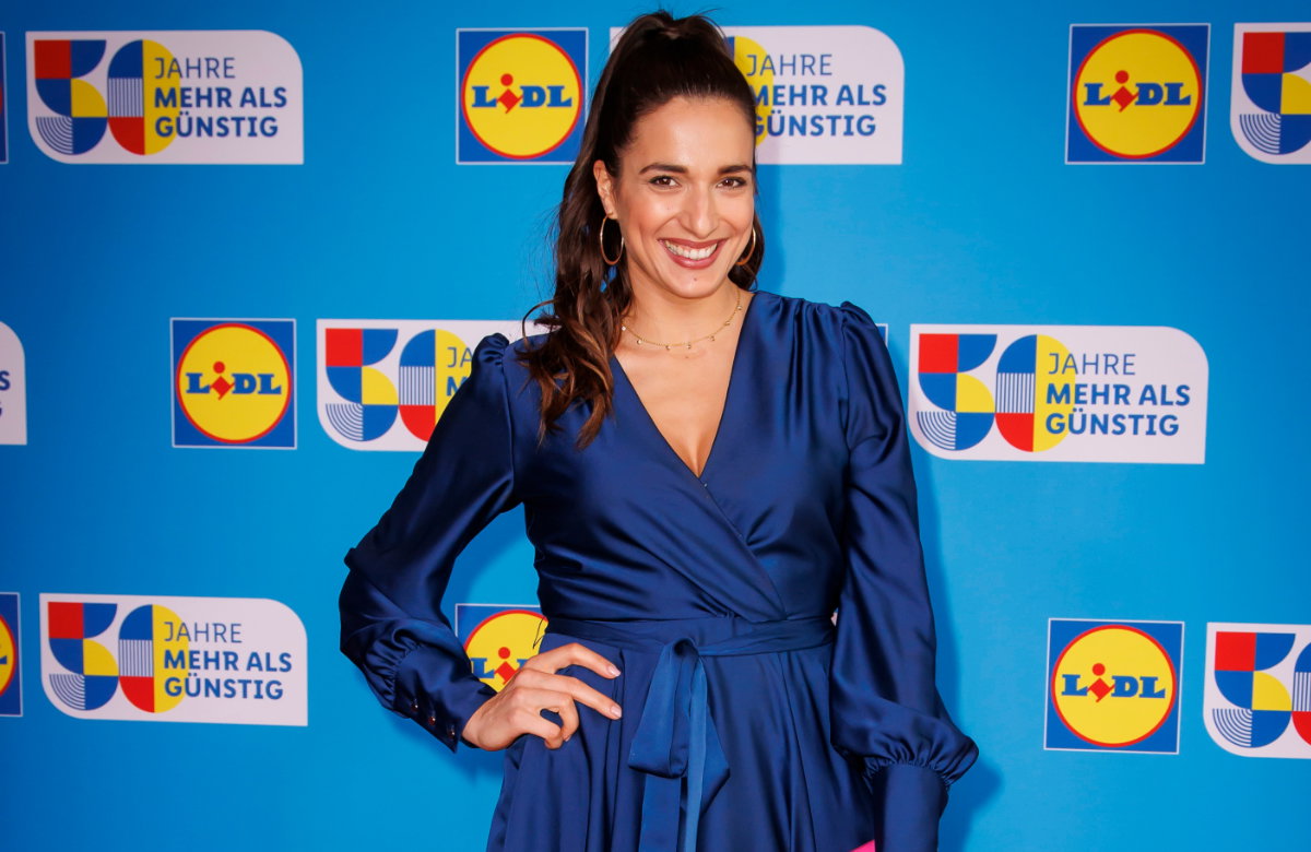 Sally Özcan lächelt im blauen Kleid