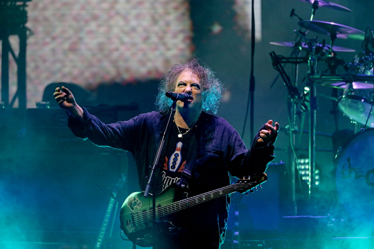The Cures Robert Smith steht auf der Bühne und breitet die Arme aus