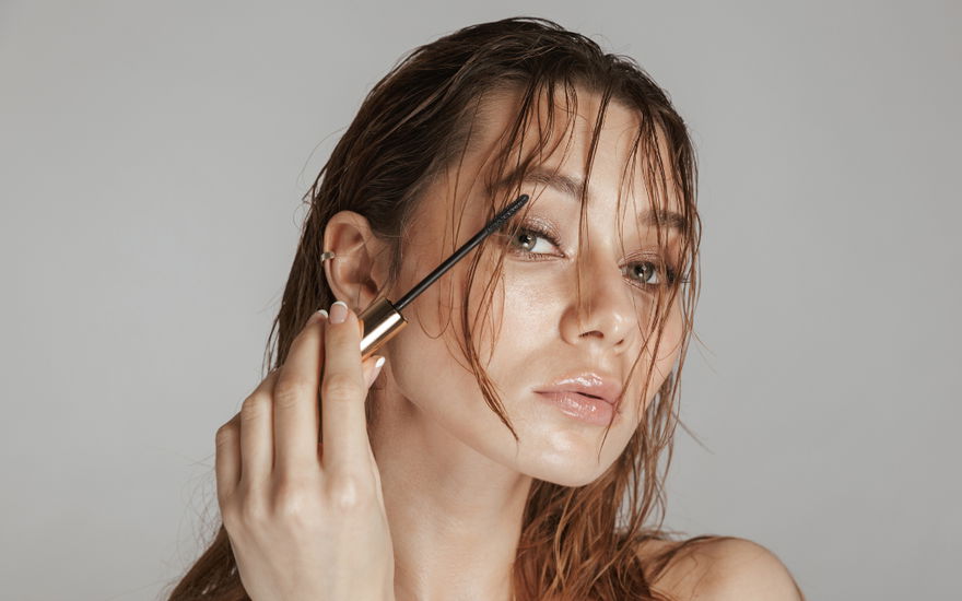Frau mit nassen Haaren tuscht Wimpern