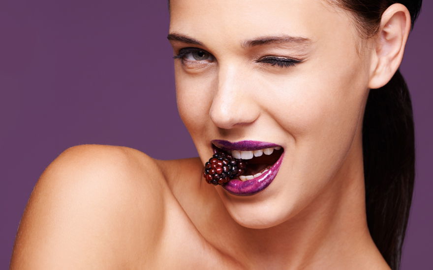 Frau mit Brombeere im Mund