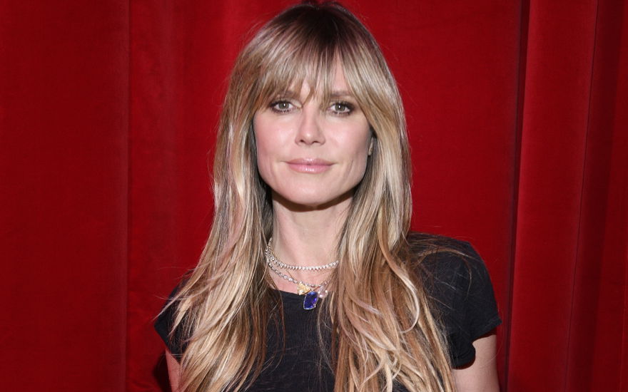 Heidi Klum steht vor einem roten Vorhang