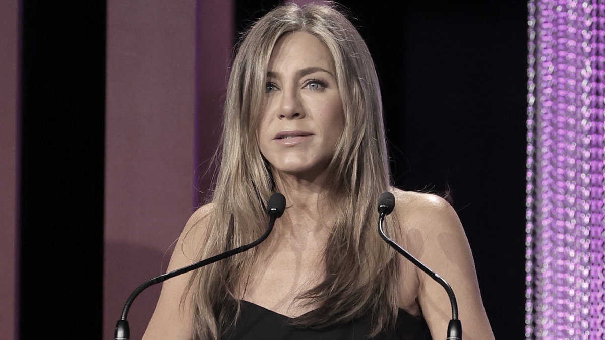 Jennifer Aniston steht mit traurigem Gesichtsausdruck am Mikrofon