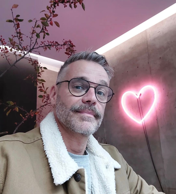 Raphael Schneider macht ein Selfie mit Herzlampe im Hintergrund.