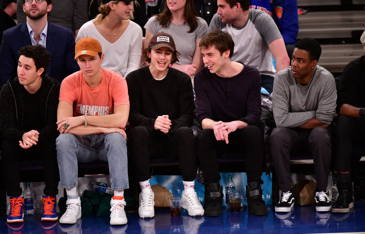 Timothée Chalamet sitzt mit Freunden am Rand eines Basketballspiels