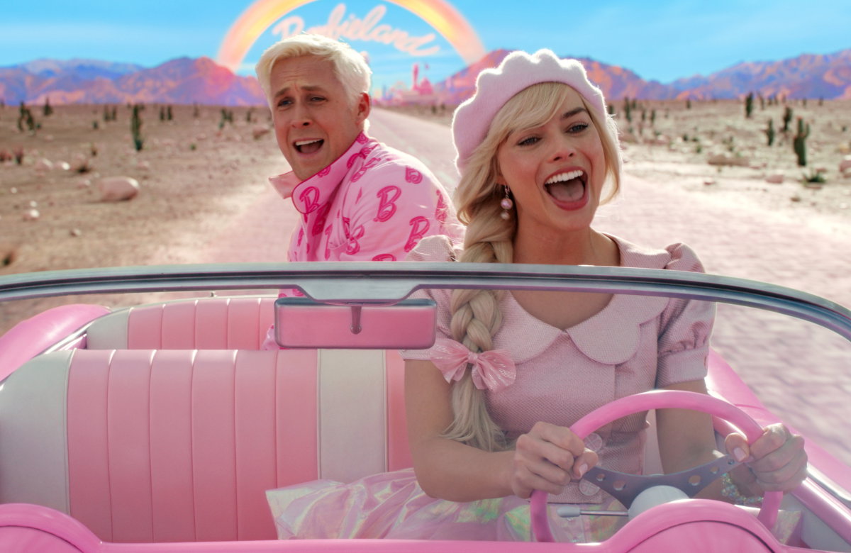 Filmszene: Ryan Gosling als Ken und Margot Robbie als Barbie im pinken Auto lachen