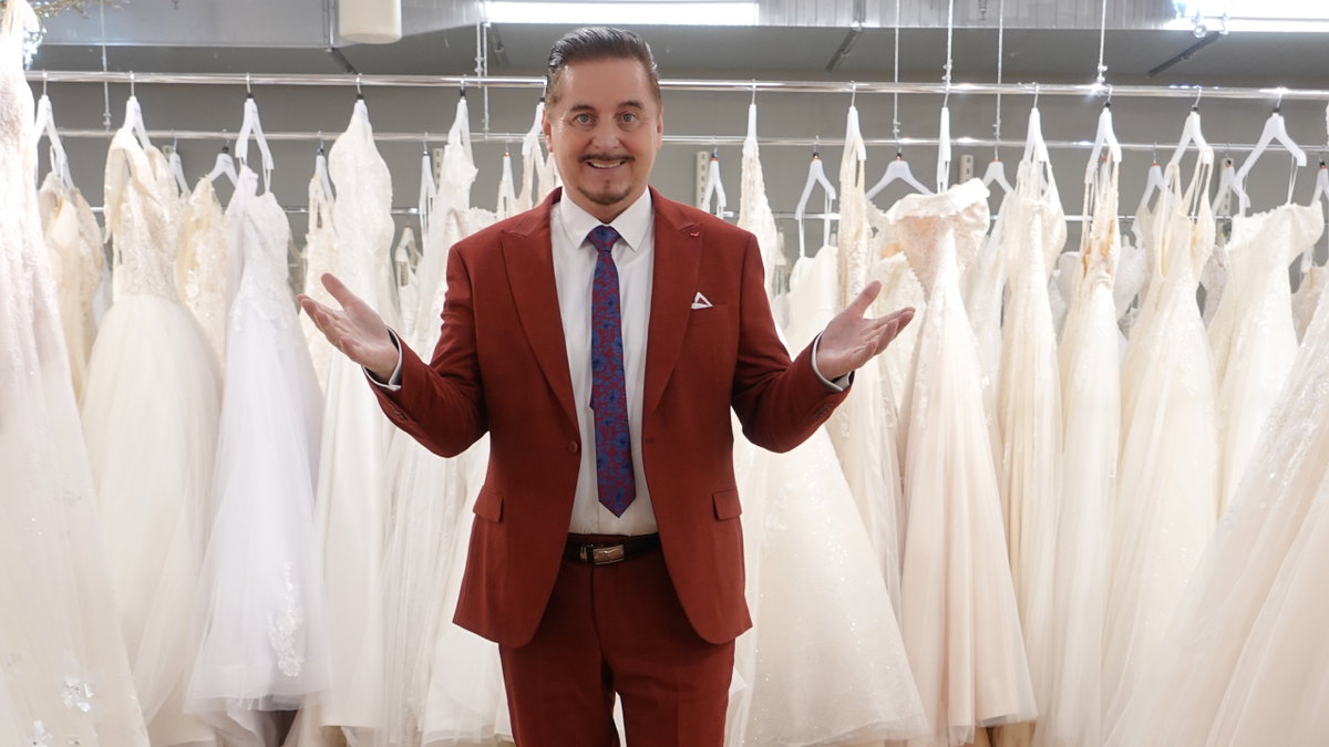 Uwe Herrmann posiert vor Brautkleidern