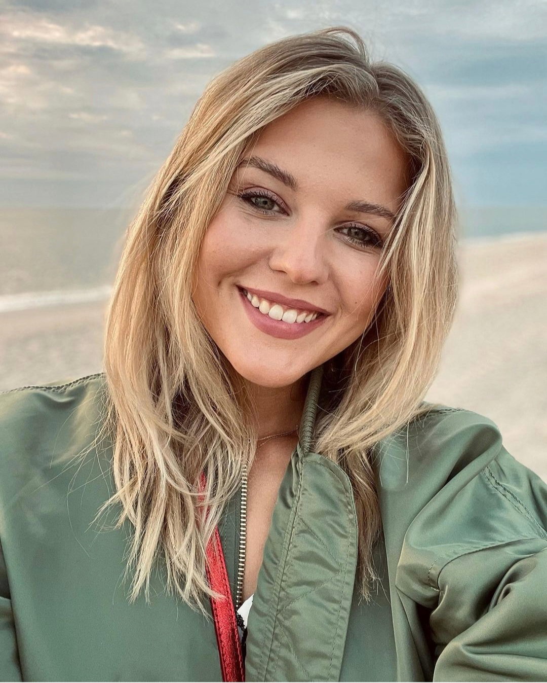 Josefin Bressel lächelt in ihr Handy am Strand.