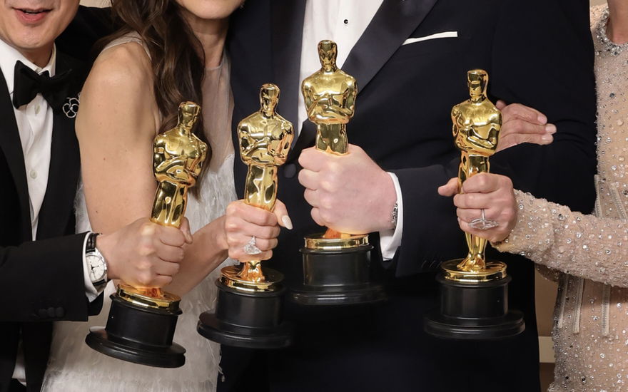Vier Personen halten Oscar-Preise in den Händen