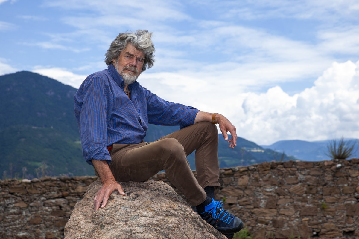 Reinhold Messner sitzt auf einem Stein