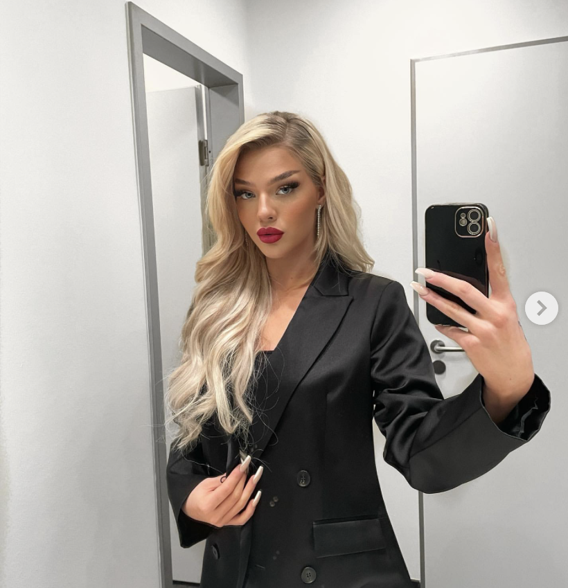 Elaine Victoria im schwarzen Blazer vorm Spiegel.