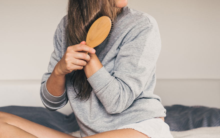 Frau pflegt Haare mit Keratin und Biotin Bürste