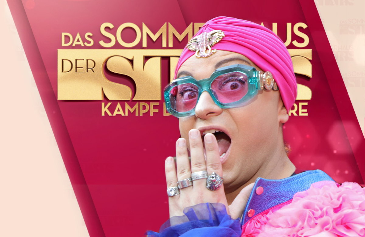 Julian F. M. Stoeckel guckt überrascht mit Hand vor dem Mund vor dem Logo von "Das Sommerhaus der Stars"
