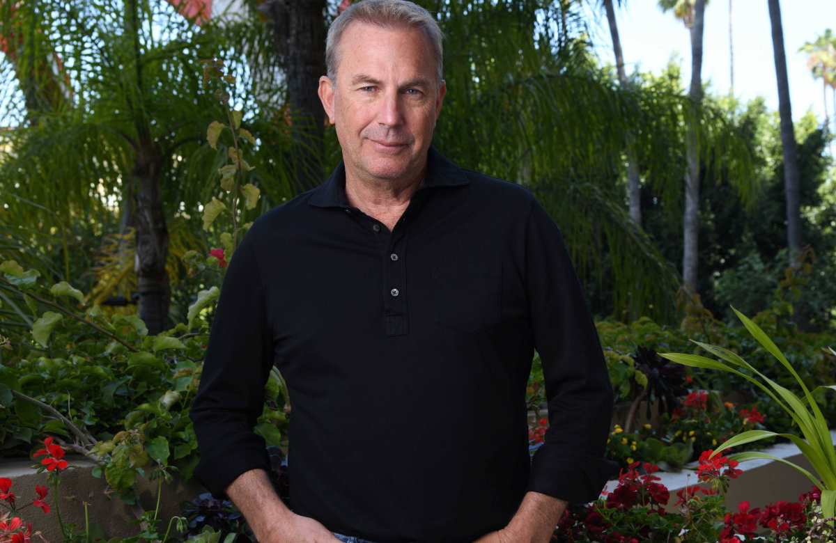 Kevin Costner lächelt leicht im Garten