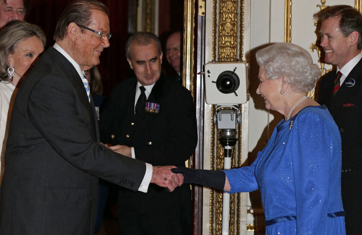 Roger Moore und Queen Elizabeth II. schütteln Hände