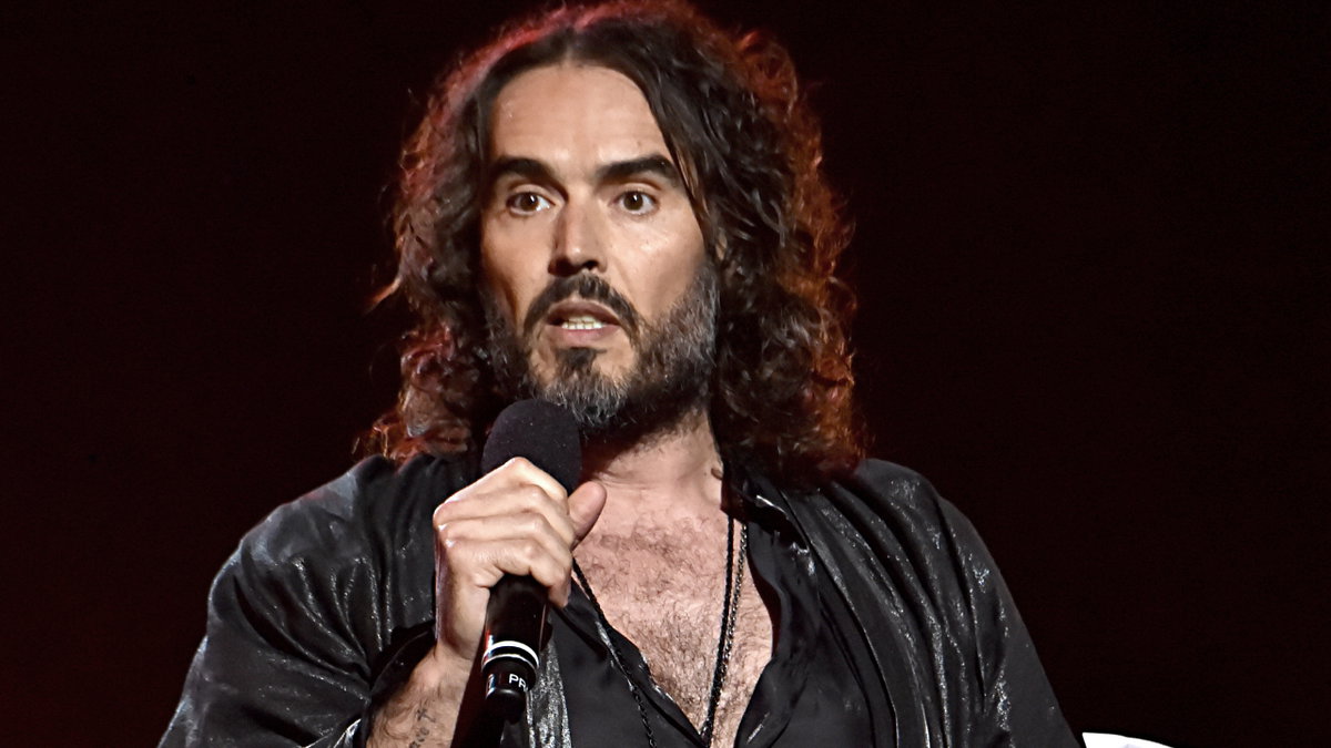 Russell Brand spricht ins Mikrofon und sieht verärgert aus