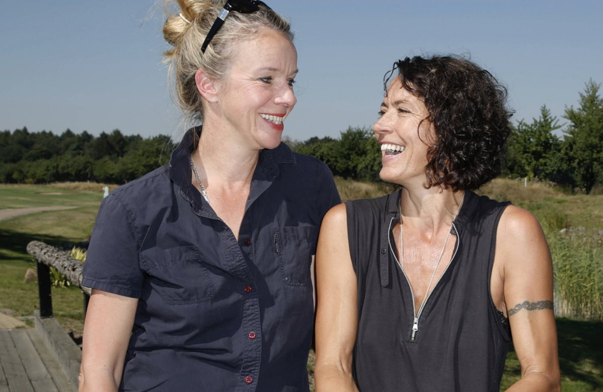 Ulrike Folkerts und Partnerin Katharina Schnitzler sehen sich an und lachen.
