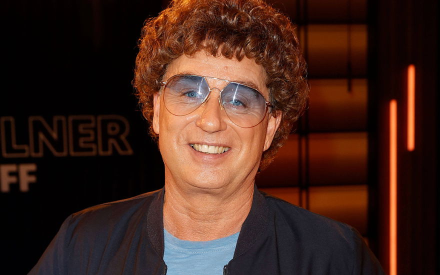 Atze Schröder lächelt mit Locken-Perüche und Brille