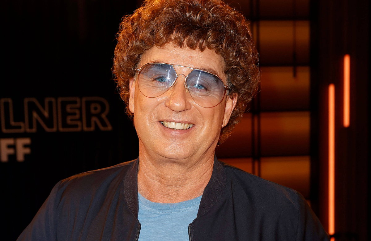 Atze Schröder lächelt mit Locken-Perüche und Brille
