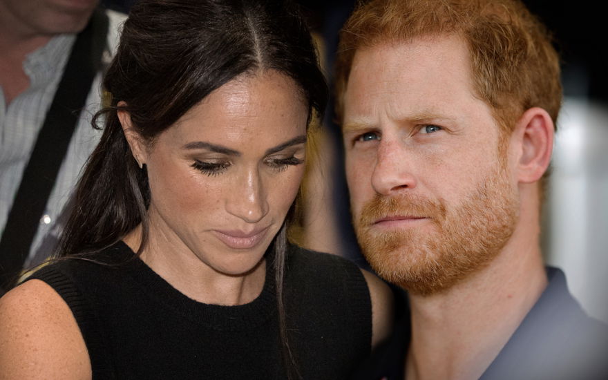Herzogin Meghan sieht zu Boden, Prinz Harry sieht nachdenklich aus