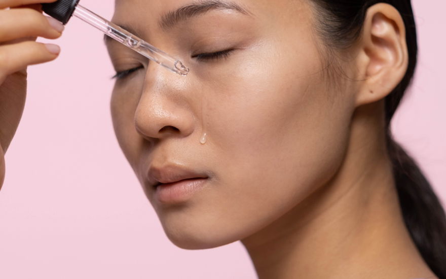 Frau trägt mit einer Pipette Retinol Serum auf das Gesicht auf