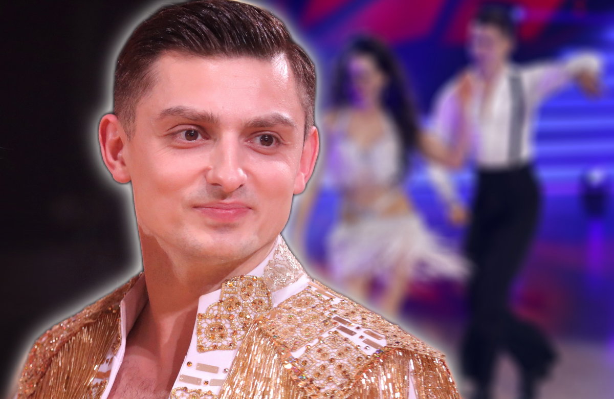 Zsolt Sándor Cseke lächelt, im Hintergrund ein verschwommenes Bild von ihm und Malika Dzumaev bei "Let's Dance"
