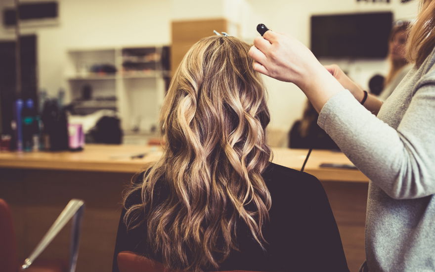 Frau bekommt mit Blowout Bürste Wellen beim Friseur